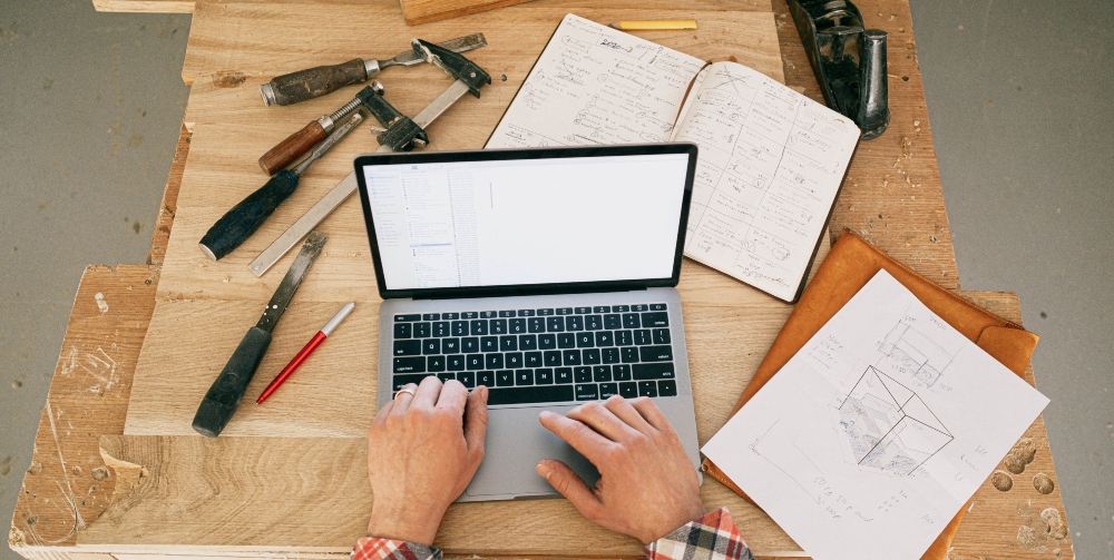 construction worker on laptop with tools on desk