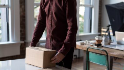 person in brown shirt packing brown cardboard box