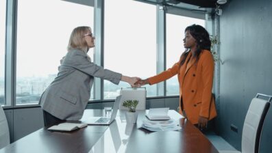 two women shaking hands over table